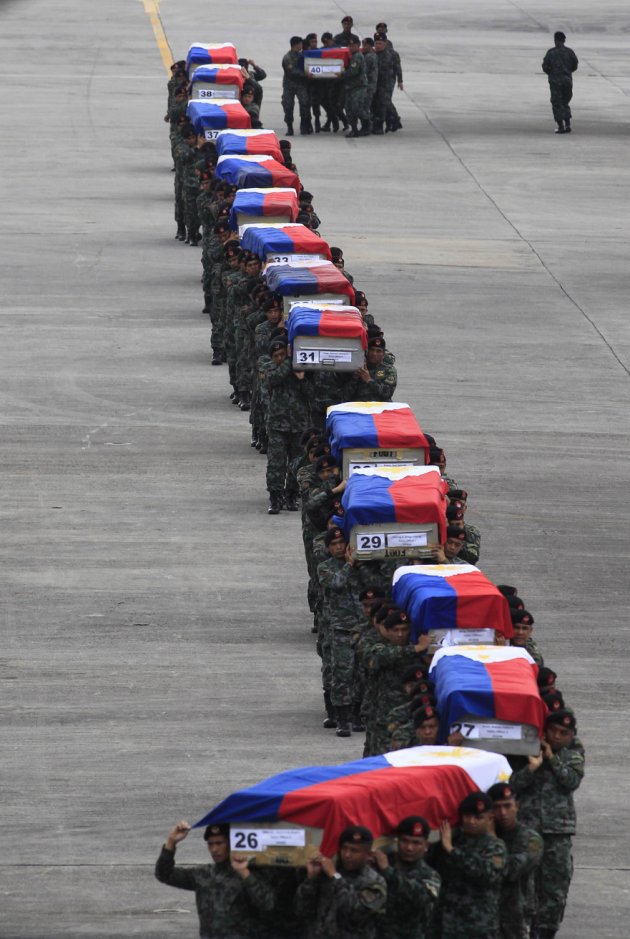 Members of the PNP Special Action Force unit carry metal caskets containing the bodies of slain SAF police who were killed in Sunday's clash with Muslim rebels, upon arriving at Villamor Air Base in Pasay city